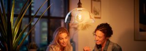 "Suspension à ampoule à filament LED de style vintage illuminant deux femmes profitant d'une conversation en soirée, créant une ambiance chaleureuse dans un appartement urbain."