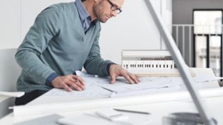Een man die thuis werkt aan een rommelig bureau
