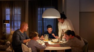 Une grande lampe suspendue à DEL illumine la table du dîner familial, créant une ambiance chaleureuse pour les repas du soir et présentant des solutions d’éclairage aérien écoénergétiques pour les maisons modernes