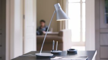 Eine Tischlampe auf einem Schreibtisch, ausgerichtet auf Papier und Stift