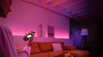 Person, die farbige Lichter im Wohnzimmer steuert