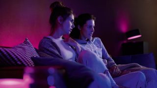 Philips Hue smart LED lights create vibrant purple and pink ambiance in living room, showcasing customizable mood lighting for movie nights and relaxation in modern homes.