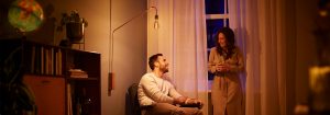 "Vintage-style LED bulb floor lamp creating warm ambiance for couple's evening conversation, showcasing energy-efficient mood lighting in cozy living room."