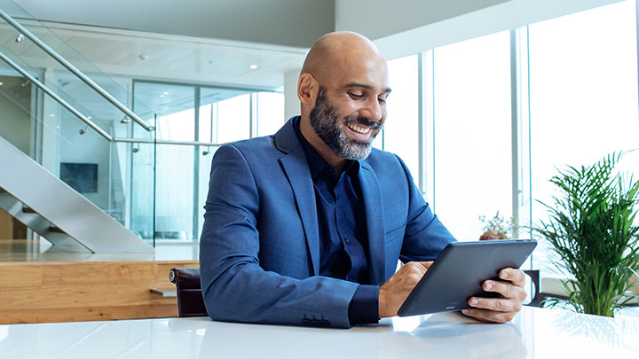 Smiling man looking at finances on smart tablet