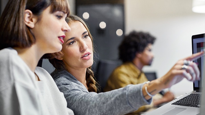 Zwei Kolleginnen besprechen ihre Arbeit am Computer