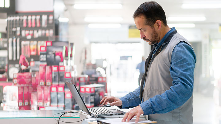 Business owner at a hardware store working on his laptop