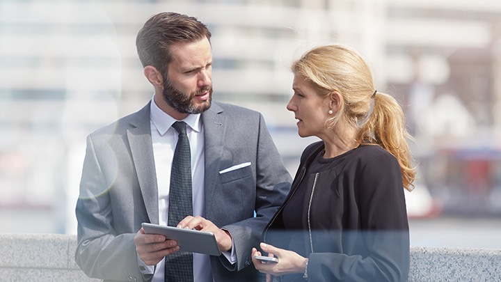 Coworkers discussing plans on a tablet in the city