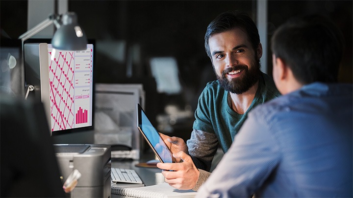 Two male colleagues on computer and tablet talking