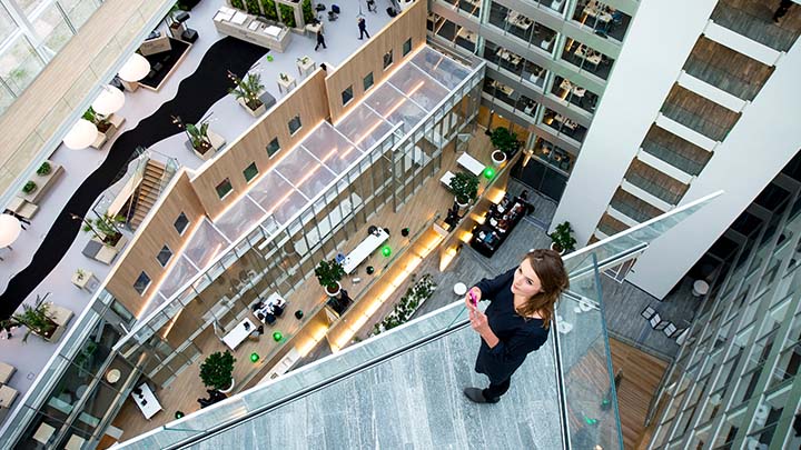 Frau in der Lobby eines mehrst&ouml;ckigen B&uuml;rogeb&auml;udes
