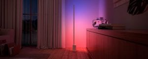 A Philips Hue Signe gradient floor lamp available in the Black Friday lighting sale washes a wall in pink and blue tones of smart light.
