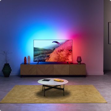 Un salon avec une lumière immersive provenant du rétroéclairage du téléviseur, synchronisée avec les couleurs de l’écran du téléviseur.