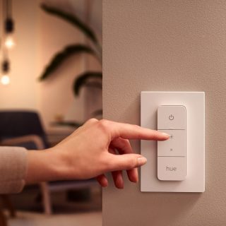 Une personne est sur le point d'utiliser un Hue dimmer switch.