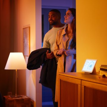 Homme et femme entrant dans une maison avec un haut-parleur intelligent 