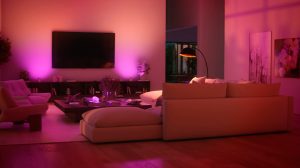 Un espace télévision dans un salon aux murs baignés d'une lumière connectée aux tons roses et violets