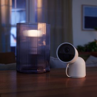 Beveiligingscamera in een smart home op een tafel naast een slimme lamp