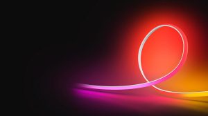 Een OmniGlow lightstrip die roze, rood en geel licht uitstraalt tegen een zwarte achtergrond. 