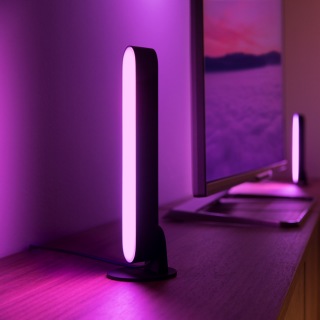 Two Play light bars placed each side of a TV screen glowing in pink smart light.