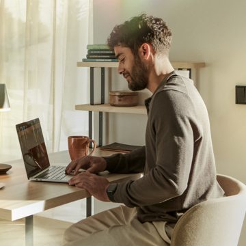 A man sits working at his laptop and monitors his front door via 2K camera.