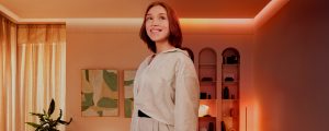 Une femme debout dans un salon éclairé par des lumières et des lampes Philips Hue.