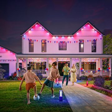Une famille passe du bon temps dans la cour avant de sa maison dont la façade est illuminée par les lumières extérieures permanentes de Festavia qui brillent en rouge, blanc et bleu pour un thème de vacances patriotique. 