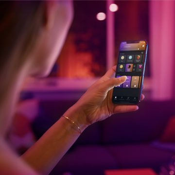 Une main tenant un appareil mobile affichant l'application Hue