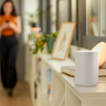 Un haut-parleur intelligent Sonos est posé sur une table de chevet et des lampes et projecteurs intelligents Philip Hue éclairent la pièce.