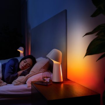 Femme dormant dans son lit avec lampe de chevet faiblement éclairée par une lumière intelligente rouge et orange