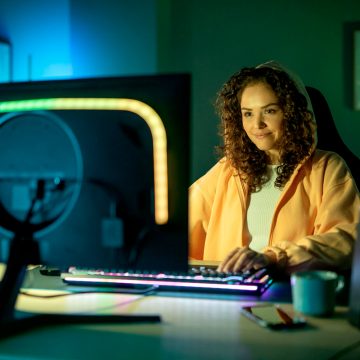 Woman gaming at a computer with colorful smart lights attached to back of monitor