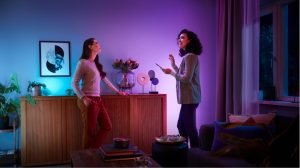Two women in a living room washed with soft tones of blue and purple smart light,