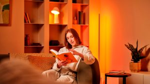 Een vrouw leest een boek op de bank, met Hue lampen achter haar.