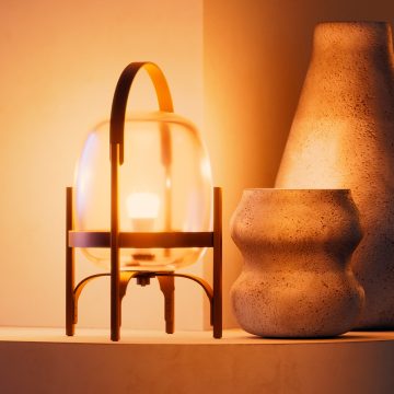 Een A19 smart lamp gemonteerd op een glazen tafellamp die oplicht in een warme tint wit smart licht