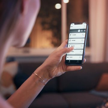 Kvinna håller i en telefon som visar smart belysningsapp