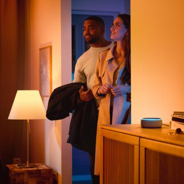 Man och kvinna som går in i ett hus med en smart högtalare 
