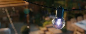 En Lightguide-ljuskälla på en slinga med Festavia-globlampor utomhus som lyser klart i ljusrosa. 