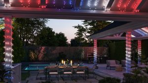 Outdoor string lights in red, blue, and white wrapped around pergola columns and ceiling, illuminating patio dining and seating areas.