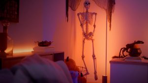 Halloween-skelet, der hænger på væggen, oplyst af et uhyggeligt orange lys. 