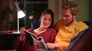 Et par læser et blad sammen ved hjælp af en bordlampe indstillet til køligt, klart lys