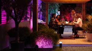 Mennesker spiser middag på en terrasse, der er badet i farverigt intelligent lys