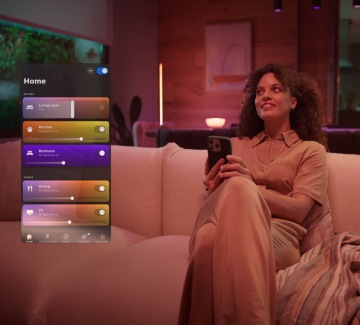 Frau auf einem Sofa mit Smartphone in der Hand und einer Ansicht der Philips Hue App.