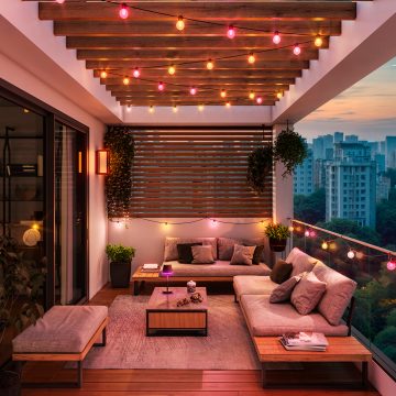 An outdoor ceiling area lit with strings of Festavia globe lights shining in pink, yellow and orange tones of smart light