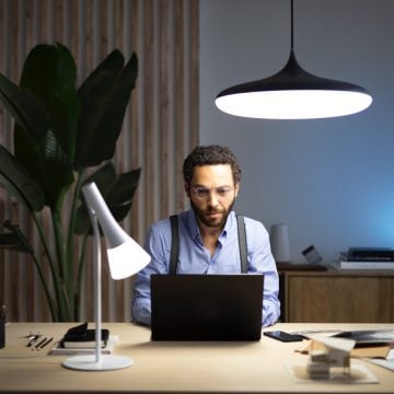 Man sitting in front of laptop at desk with two smart lamps