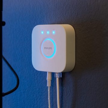 The Hue Bridge device hangs on a blue-colored wall.