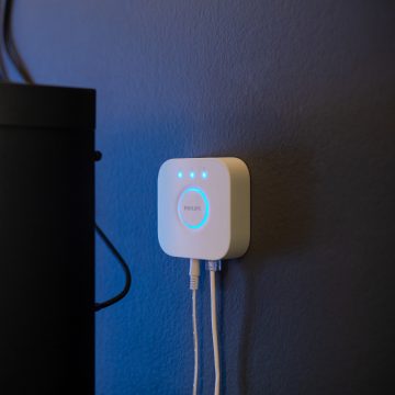 Philips Hue Bridge with cables turned on hanging on a wall