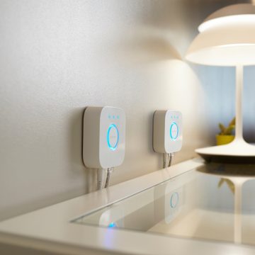 Two Hue Bridges mounted on a wall behind a table with lamp