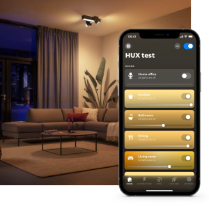 Modern living room with smart lighting overhead and a smartphone displaying the HUX test app for controlling lights in multiple rooms.