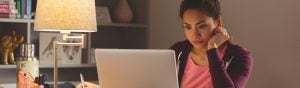 Woman looking at laptop with smart table lamp on in background