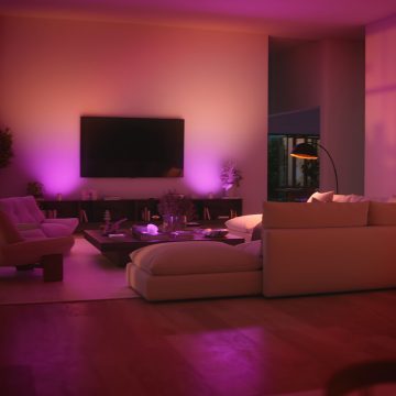 A living room lit in pink and purple tones of wall washing smart light with Hue Play wall washer.