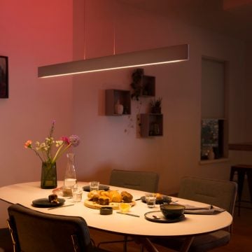 Long horizontal pendant light hanging above dining room table