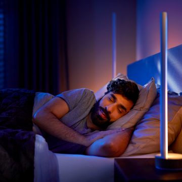 Man sleeping next to bedside lamp with dimmed lights