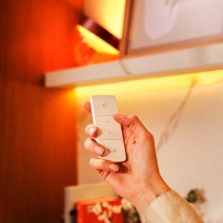 Una mano sosteniendo un mando a distancia para atenuar sus luces.